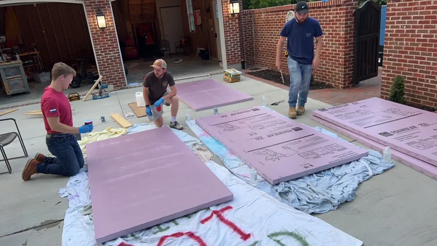 Stacks of pink foam sheets laid out on a driveway for gluing.