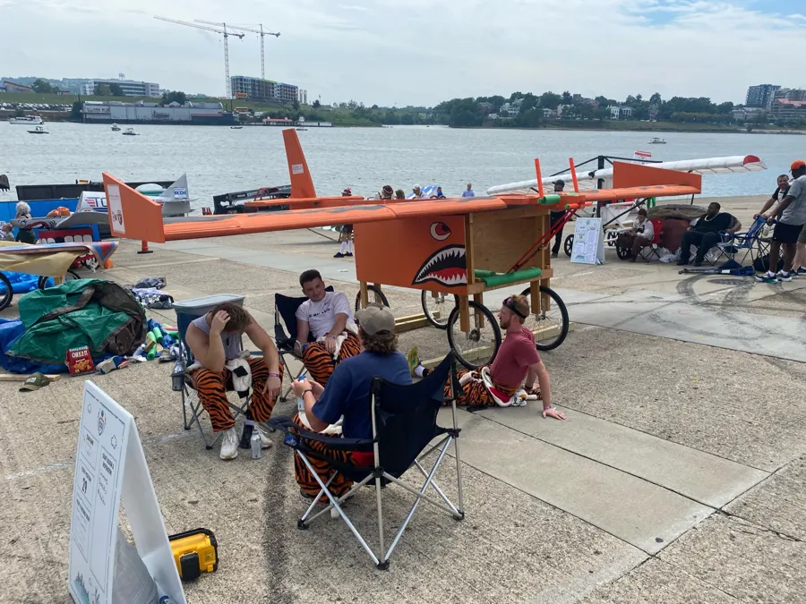 The finished glider on its cart in the riverfront staging area, with the team nearby.